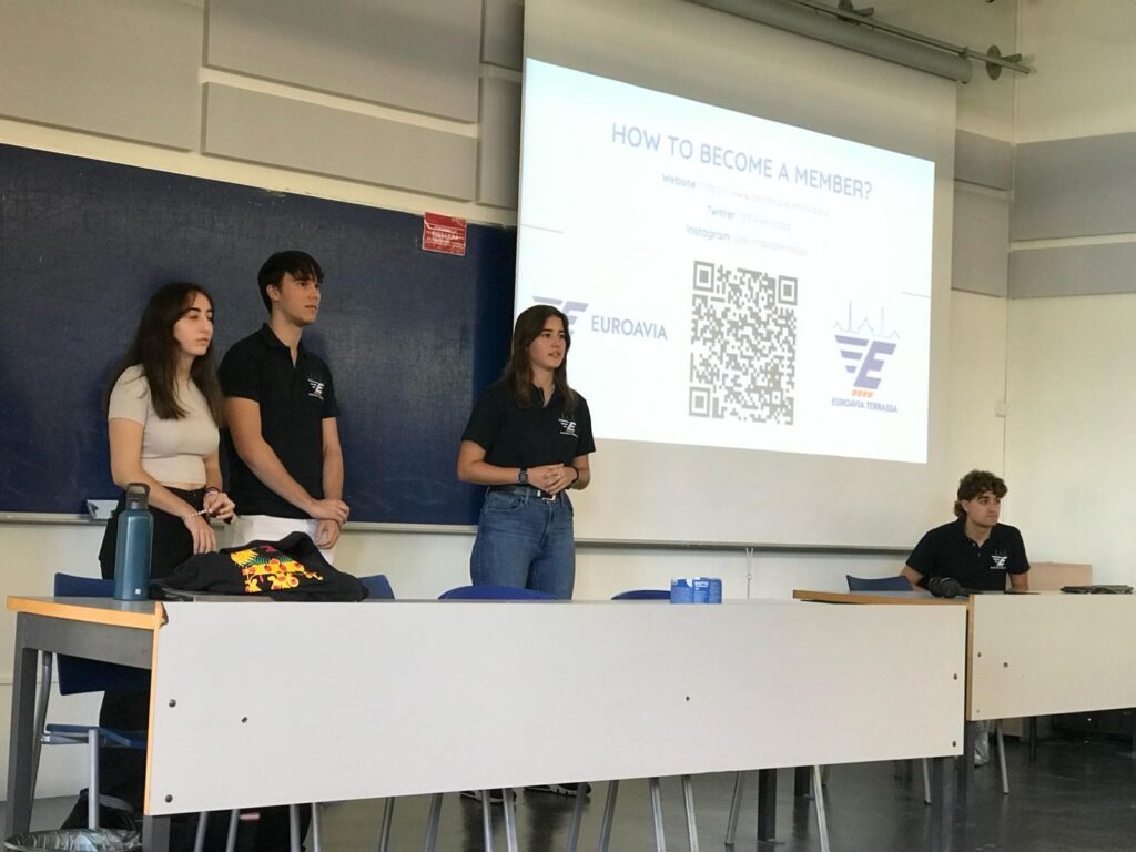 Amanda giving a presentation about how to become a member of AS Terrassa. The photo shows four people standing with a powerpoint presentation behind them.
